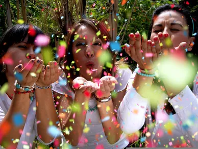 Many people are celebrating and blowing confetti from their hands.