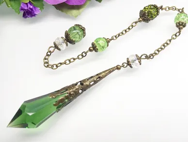 A jade gemstone pendulum is attached to a gold chain.